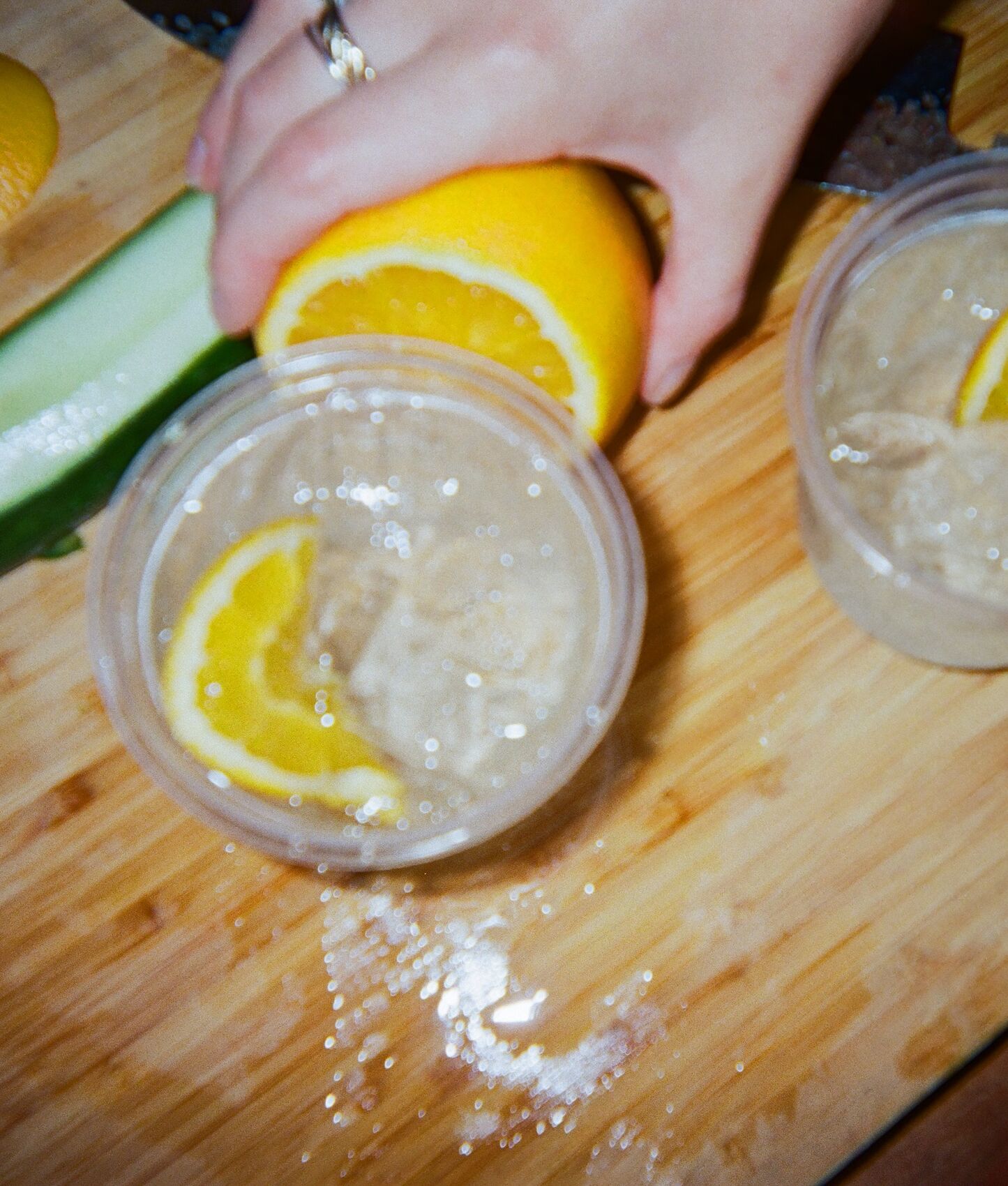 An orange wheel going into two iced spritzes on a chopping board