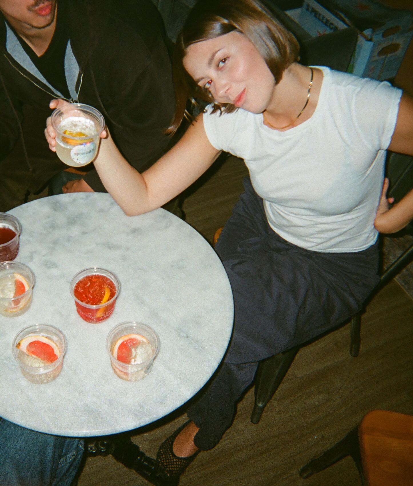 A guest leaning over a marble table of spritzes, holding one up to the camera