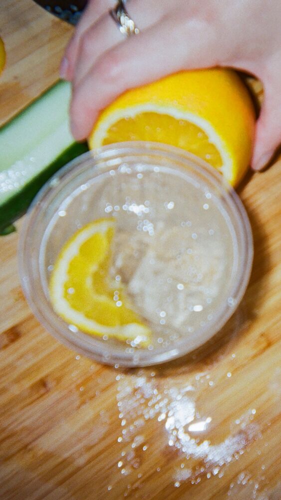 An orange wheel going into two iced spritzes on a chopping board