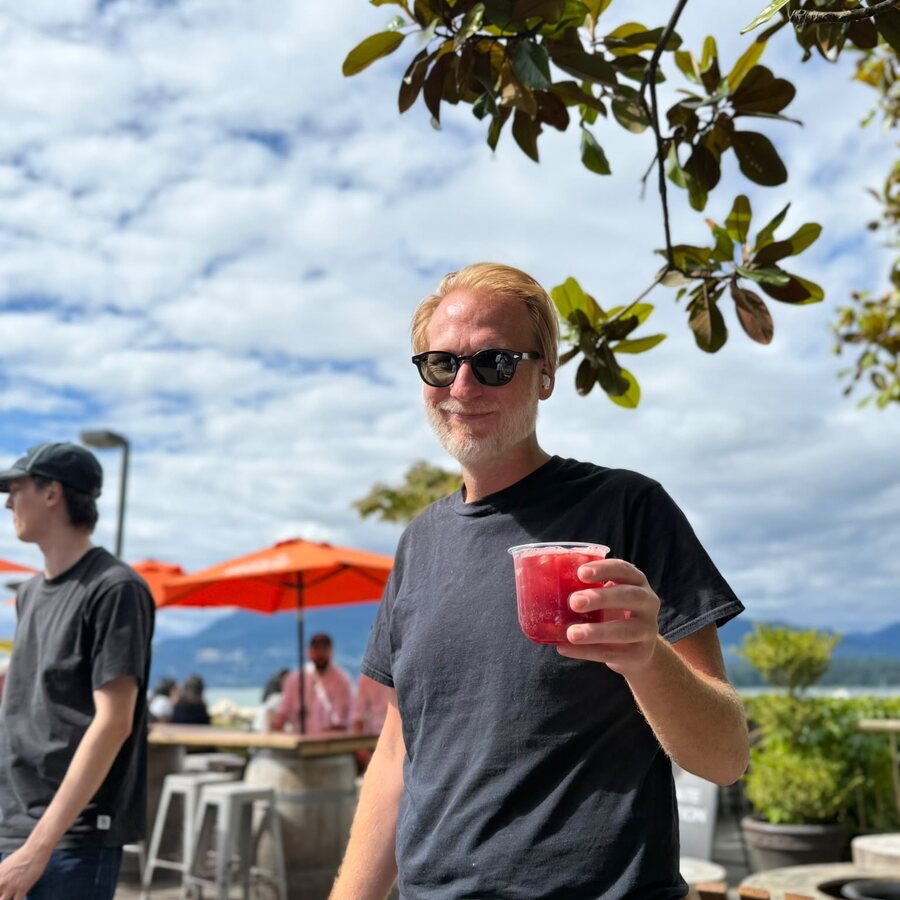 A guest outdoors under a magnolia tree holding a red Sprizzini spritz